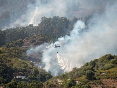 A helicopter drops water over a forest fire raging in the Moya Mountains on the island of Gran Canaria, Spain, on Aug. 19.