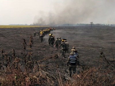Firefighters walk through a burnt field as they combat a fire in the surroundings of Robore in Bolivia on Aug. 23.