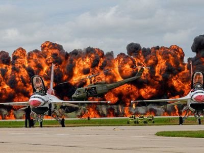 Aircraft from the US Air Force Thunderbirds display team sit on the tarmac while a helicopter picks up a downed pilot amid a pyrotechnics simulation during a Vietnam War re-enactment at the Sioux Falls Airshow in South Dakota.