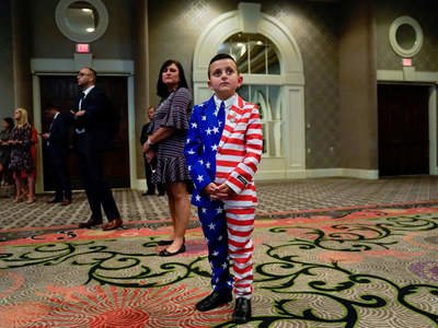 Reed Elliotte stands in the back of the room in a US flag outfit with his mother, Larrietta, listening to President Donald Trump address the American Veterans convention in Louisville, Kentucky, Aug. 21.